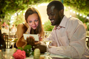 He made a special video to declare his love. Cropped shot of a man showing his girlfriend something on his cellphone while on a date.