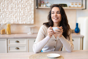 Good morning, rest and enjoy weekend. Happy relaxed caucasian woman drinking coffee in modern kitchen and dreaming