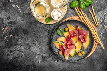 Cantaloupe melon with prosciutto or jamon and green basil leaves with glass of wine. delicious...