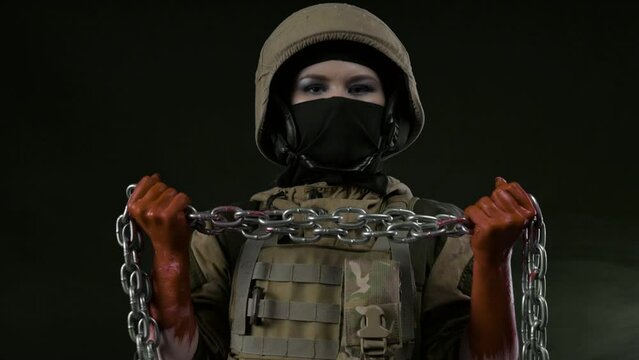 girl soldier in a helmet holds a chain with bloody hands as a symbol of slavery