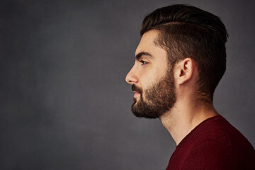 Handsome from every angle. Studio shot of a handsome young man posing against a dark background.