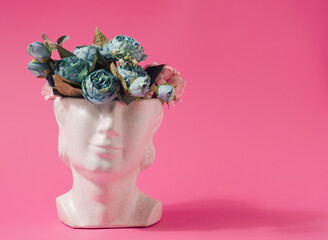 Marble statue head with spring flowers inside. Summertime colorful background.