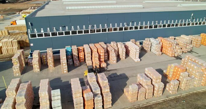 A forklift is driving through a manufacturing warehouse. Warehouse under the open sky.