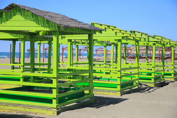 Plank arbors for relaxing in bright green on the beach on a bright sunny day.