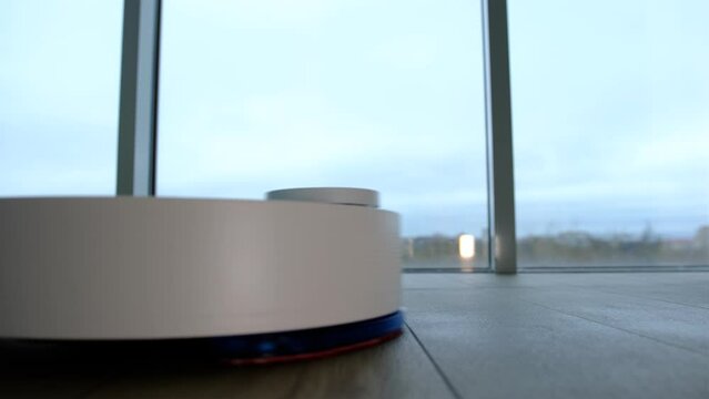 Robot vacuum cleaner vacuuming the floor. Smart home with automated devices that simplify life. A smart vacuum cleaner cleans the floor.