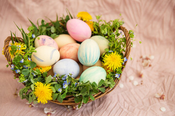 On a pastel cover a basket with herbs and bright flowers. The basket contains Easter eggs painted in watercolor in beautiful pastel colors. Great Easter.