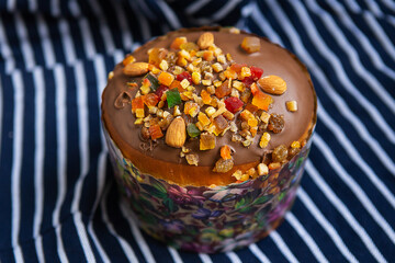 An Easter cake decorated with candied fruits stands on a striped blue apron. Easter religious holiday concept.