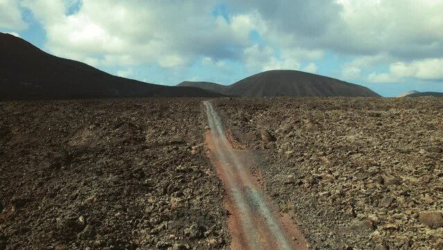 Drone point of view Timanfaya National Park, rocky volcanic landscape and mountains on blue cloudy sky background. Canary Islands, Lanzarote, Spain. Travel destination, famous places concept	
