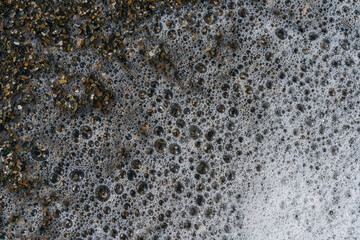 top view of a foamy sea wave breaking on a summer pebble beach