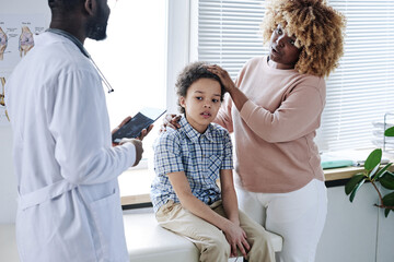 African mother talking to doctor about her son during medical exam at hospital