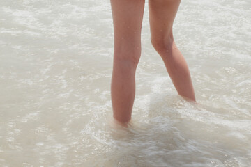 Girl's legs on the seashore during a sunny summer day, Spain