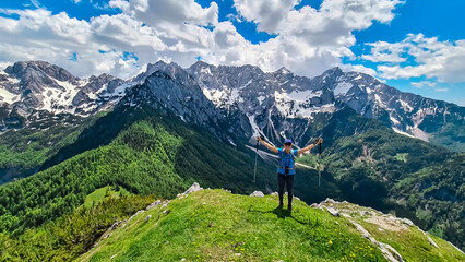 Fototapeta na wymiar Happy woman spreading her arms out of joy on the summit of Goli Vrh with scenic view on mountains Kamnik Savinja Alps in Carinthia, border Slovenia Austria. Vellacher Kotschna. Mountaineering. Freedom