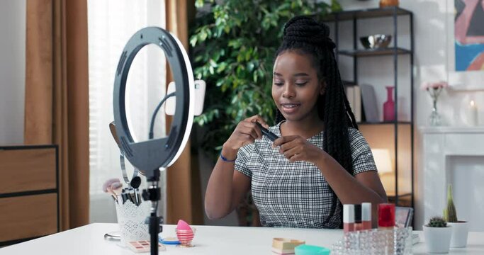 Influencer records product reviews of the brand she works with via social media. Makeup tutorial, lifehacks on how to paint eyelashes. A woman opens cosmetics and uses mascara on her lashes.