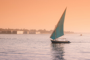 felucca is a traditional sailing boat used for tourist transport and cruise down the Nile in Luxor city in Egypt at romantic sunset time