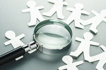 Magnifying glass on many paper human dolls, man management, human resources analytics, search the...