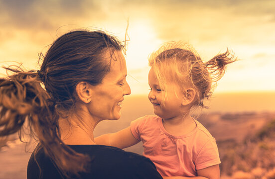 Portrait of happy mother and her little girl smiling feeling free at sunset. 