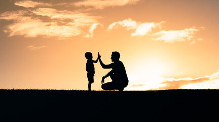 Fototapeta na wymiar Father encouraging in child giving him a high five. Happy father son moment outdoors. Parenting and raising children concept. 