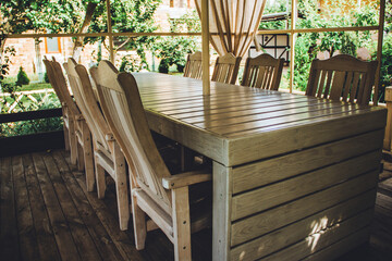 Wooden table and wooden chairs. Wooden white gazebo in the summer garden. White garden furniture. Rest and relaxation in the private garden