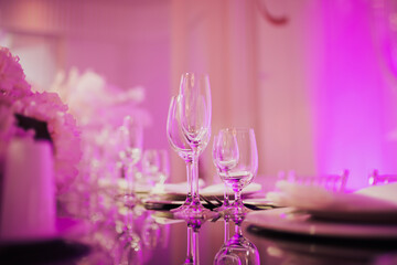 Table setting for an event party or wedding reception in the luxury restaurant in purple light.