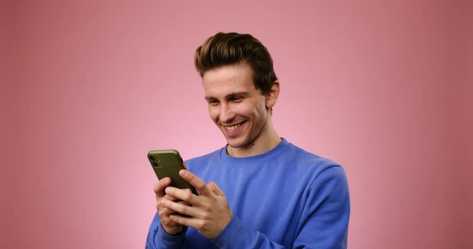 Happy man text messaging on mobile phone over pink background
