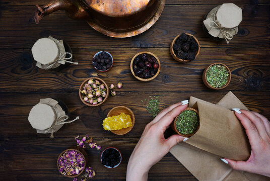 Women's hands pour a mixture of herbal tea into a bag