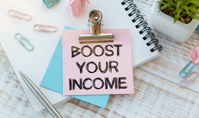 BOOST YOUR INCOME text on sticker on diagram with pen and flower.