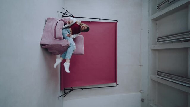 A girl on a pink photo background shakes her legs in a chair