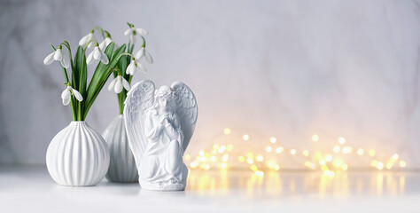 angel and snowdrops flowers on table, light abstract background. Religious church holiday. symbol...