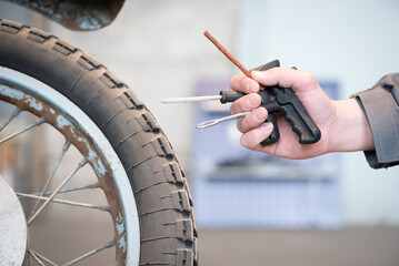 Wheels repair kit in the worker hand on the deflated motorcycle wheel close up.