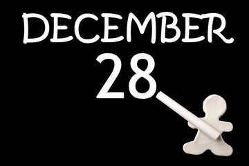 28th day of December. A small white plasticine man writing the date 28 December on a black board. Business concept. Education concept. Winter month, day of the year concept.