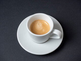 a white coffee mug with a full espresso is set on a saucer and on a black background. Coffee,...