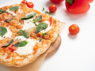 Close-up of a delicious Roman pizza with vegetables on a white background. ripe red tomatoes and micro-greens lie nearby. Traditional Italian food. Side view