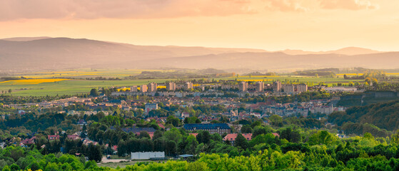 Kłodzko, panorama of the city in the valley against the background  of the mountains lit by bright sun at sunset. - obrazy, fototapety, plakaty