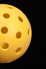 Yellow half Pickleball with black background.