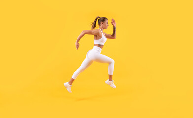 energetic fitness woman runner running on yellow background