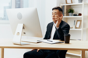businessmen in a suit glass of coffee sits at a tablein front of a computer Lifestyle