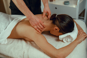 Professional masseur man doing back massage for female client at spa center. Relaxation, therapy salon