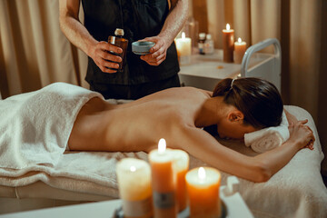 Obraz na płótnie Canvas spa beauty salon therapist preparing warm herb infused oil for female back massage