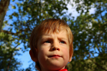 Portrait of a serious blond boy with dirty lips. A five-year-old boy looks into the distance with a frown.