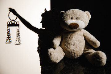 Silhouette of lady of justice on white background and teddy bear