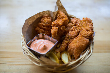 Chicken wings in a basket, with French fries and sauce
