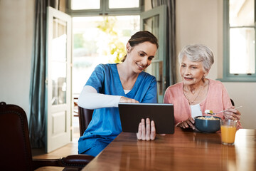 See how easy it is to use. Shot of a young nurse and senior woman using a digital tablet at...