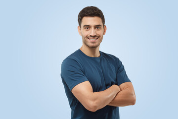 Athletic young sporty man in blue t-shirt standing with crossed arms