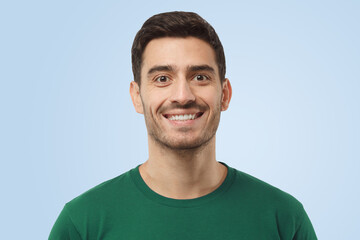 Fototapeta premium Attractive optimistic smiling handsome man in green t-shirt looking at camera