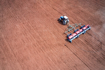 Tractor with a seeder on arable land. Direct sowing of grain with simultaneous application of fertilizers to the soil. Shooting from a drone.