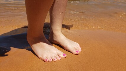 Bare feet with a pedicure on a beach vacation