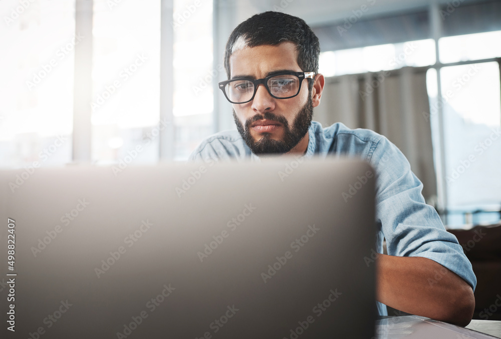 Poster The digital worker will always get things done. Shot of a young man using his laptop while working from home.