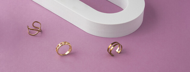 Panorama of three modern design rings on white and purple background with copy space