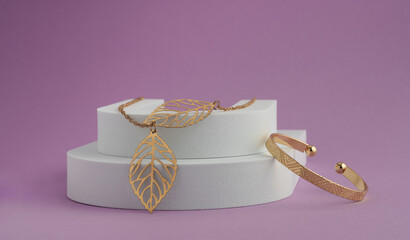 Leaf shape Necklace pendant and geometric pattern bracelet on white podium on purple background