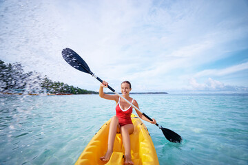 Active vacation. Young woman paddling the sea kayak near tropical bay.